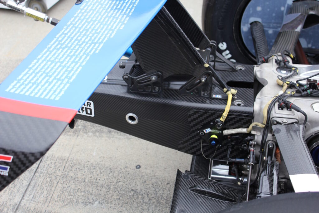 The checkered ‘U’ shaped indentation on the horizontal rear wing support panel is the area in question. The Penske Team filled in the ridge line, smoothing out the panel. The pictured panel is correct.